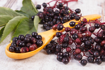 Heap of elderberry with wooden spoon on old wooden background, healthy food