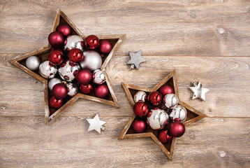 Christmas wallpaper with red and silver decoration in star shapes on wood background with copy space