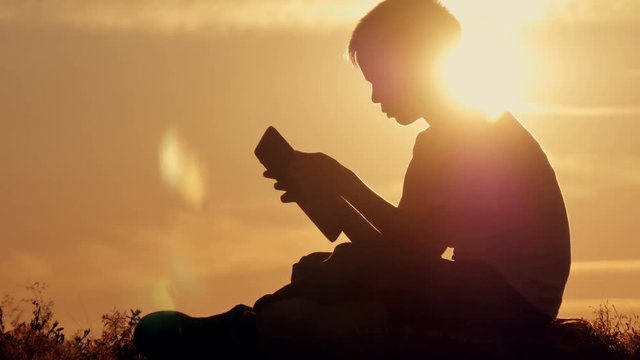 Man silhouette sitting under tree with tablet on cloudy day outdoor