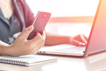 Close Up of woman hands using mobile phone and laptop computer business with blank copy space screen for your business advertising text message or content business in the morning light.