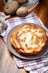 Stack of potato pancakes on a wooden table. In the background po