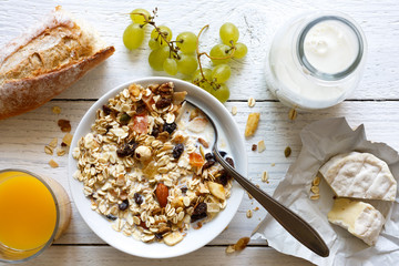 Healthy breakfast with muesli, grapes, cheese and juice on rustic table.