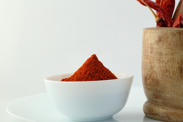 red chillies with red chilly powder on white background