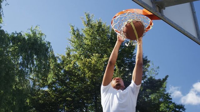  Basketball player slam dunks and hangs on the rim, in slow motion