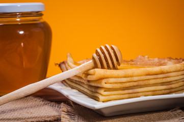 Fresh honey with a Stack of blinis or crepes