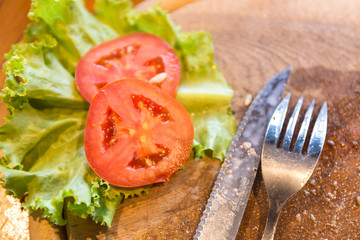 after eating Spoon, knife , lettuce, tomato on wood plate