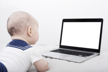 Infant lying down looking at the computer with copyspace 