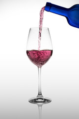 Wine glass with red wine pouring in it with reflection