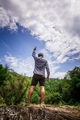 man standing behind show victory sign in forest with blue sky