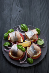 Canapes with herring fillet on a black wooden background
