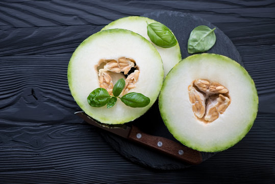 Above view of ripe sliced melon on a black wooden background
