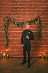 Wedding ideas, groom in black suit standing near decorated wall