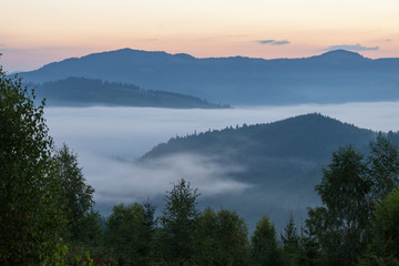 Amazing scenery of idyllic countryside with rolling hills veiled in morning fog. Aerial view  a hilltop farmhouse on  foggy spring