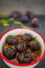Oven-baked figs with herbs and spices with honey on baking dish.