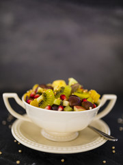 Delicious and healthy fresh fruit salad in bowl. Vegetarian food on dark stone background with copy space.