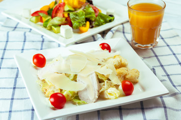 Caesar salad with chicken and greens on wooden table