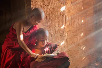 Papier Peint photo Bouddha Young Buddhist novice monk reading and study outside monastery