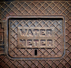old rusted water meter cover on sidewalk