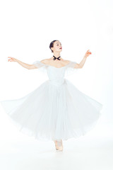 Fototapeta na wymiar Ballerina in white dress posing on pointe shoes, studio background.