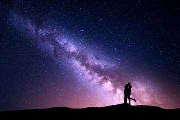 Milky Way. Night landscape with silhouettes of hugging and kissing man and woman on the mountain....