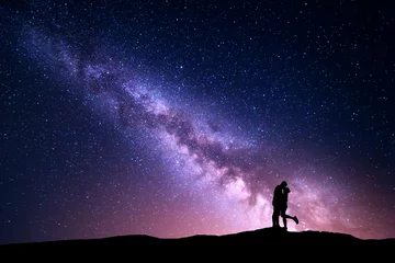  Melkweg. Nachtlandschap met silhouetten van knuffelen en kussende man en vrouw op de berg. Kleurrijke hemel met sterren. Silhouet van geliefden. Paar, relatie. Melkweg met mensen. Universum © den-belitsky