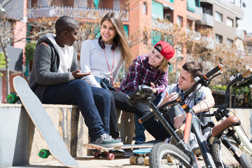 girl and three boys hanging out outdoors and discussing somethin