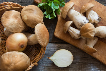 Fresh white mushrooms in basket and ingredients for mushroom's cream-soup on a rustic wooden board, overhead view.