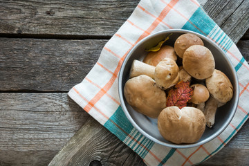 Fresh white mushrooms from  forest in basket on a rustic wooden board, overhead view.