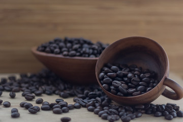 coffee beans in wooden bowl and mug on a wooden background