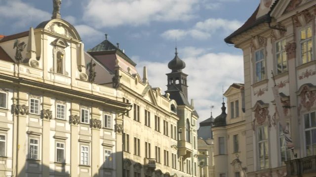 Pan across ornate buildings in old town square Prague as white clouds fly overhead