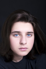 A portrait of a handsome blue eyes teenager on dark background