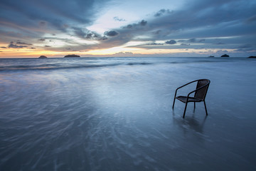 Fototapeta na wymiar Chair in sea at sunset, long time of shutter speed