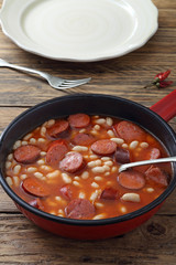 salsicce e fagioli con salsa di pomodoro in padella di metallo sfondo rustico