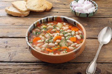 zuppa di fagioli bianchi con verdure su sfondo tavolo di cucina rustico
