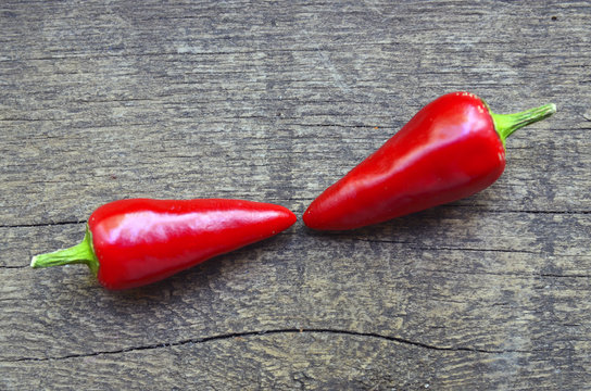 Two red chili peppers on old wooden background.Selective focus.Copy space.