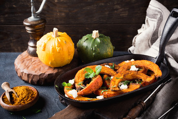 Spicy roasted pumpkin with goat cheese and mint on a cast iron skillet. Healthy food concept.