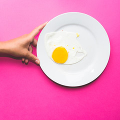 single fried egg  on body part, food art minimal set design