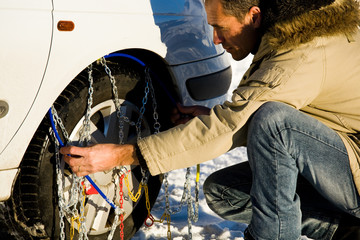 man installing snow chain on his car