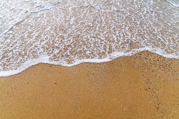 Fototapeta na wymiar Foam wave on sea close with beach background