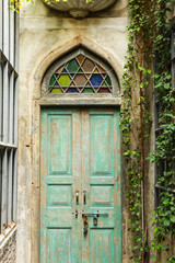 Fototapeta na wymiar green wood door and a wall covered with green leaf