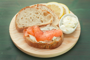 smoked salmon with bread and fresh cheese on wooden board
