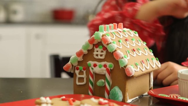 Closeup of young girl decorating gingerbread house for Christmas