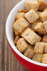croutons in red bowl on wooden background