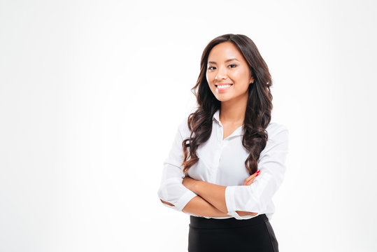 Smiling pretty young asian businesswoman standing with arms crossed