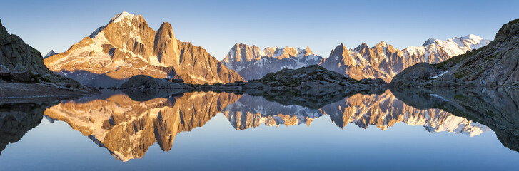 Panorama of Alps mountain range, sunset lights, reflection in lake