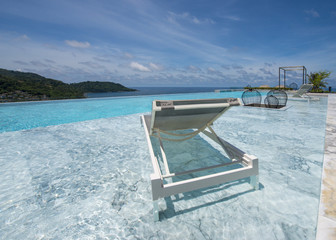 Luxury swimming pool and deck chair at the resort with beautiful sea view