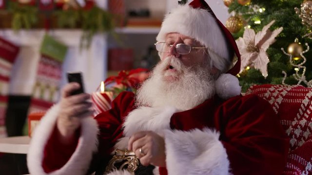 Santa Claus texting with cell phone and taking selfie