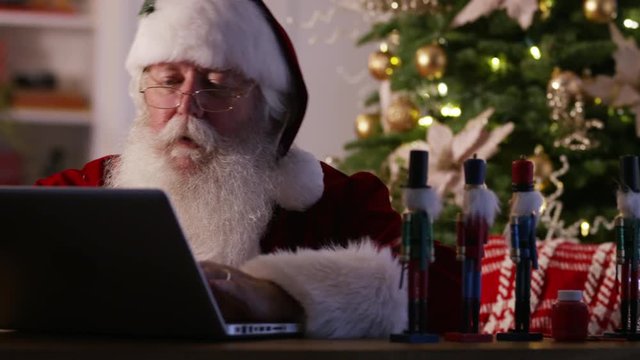 Santa Claus in workshop using laptop computer
