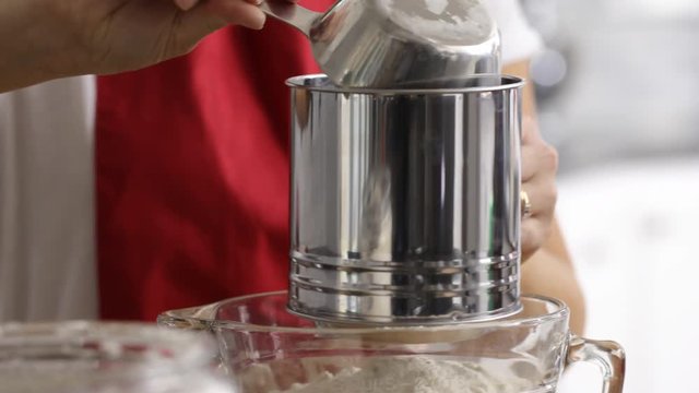 Closeup of woman sifting flour in kitchen