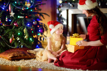 Fototapeta na wymiar Happy little girl getting a Christmas gift from her mommy